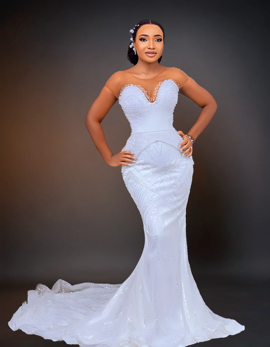 A stunning luxury wedding dress that features intricate beading and a long cape. It has a removable overskirt that adds versatility to the design.