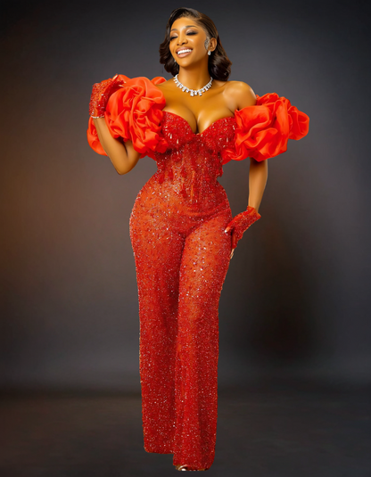  luxurious red jumpsuit designed for prom. It features intricate sequin lace detailing, adding a touch of sparkle and elegance. 