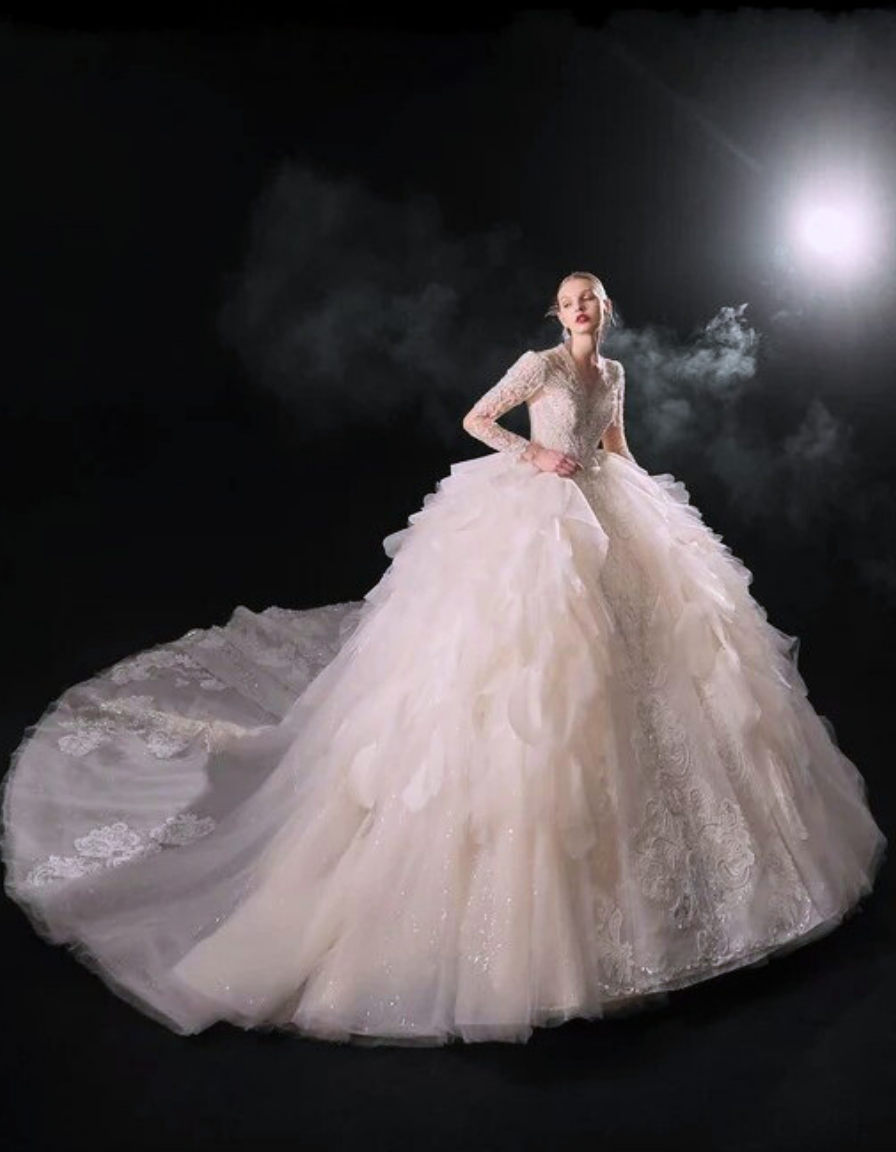 Woman in a white wedding dress with a long train against a dark background