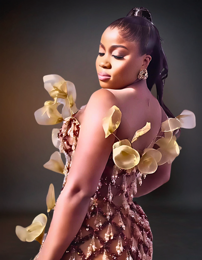 Luxury 3D prom flower dress in brown and gold, featuring intricate floral designs and embellishments, displayed on a mannequin in an elegant setting.