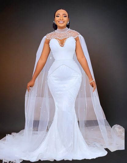  A stunning luxury wedding dress that features intricate beading and a long cape. It has a removable overskirt that adds versatility to the design. 