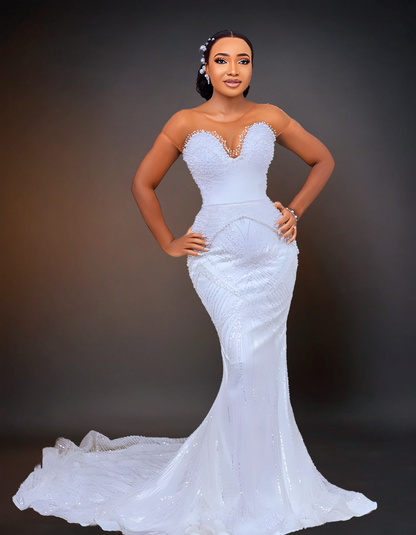  A stunning luxury wedding dress that features intricate beading and a long cape. It has a removable overskirt that adds versatility to the design. 