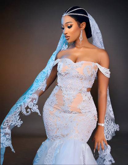 An elegant white wedding dress adorned with intricate beadwork. The gown features a fitted bodice and a flowing skirt, shimmering with delicate, shiny beads that add a touch of luxury and sophistication.