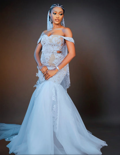 An elegant white wedding dress adorned with intricate beadwork. The gown features a fitted bodice and a flowing skirt, shimmering with delicate, shiny beads that add a touch of luxury and sophistication.