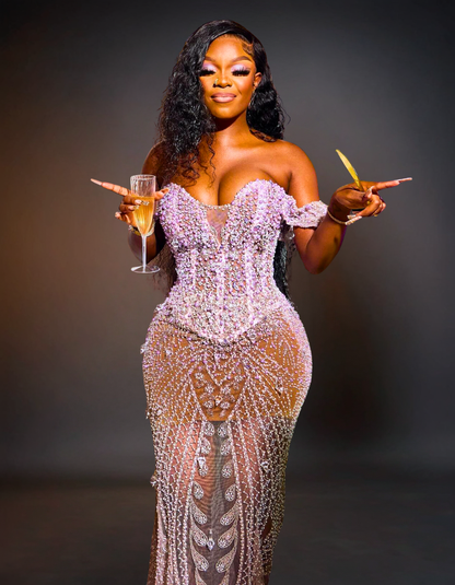 Woman in a sparkling evening gown holding a glass and a cigarette against a dark background