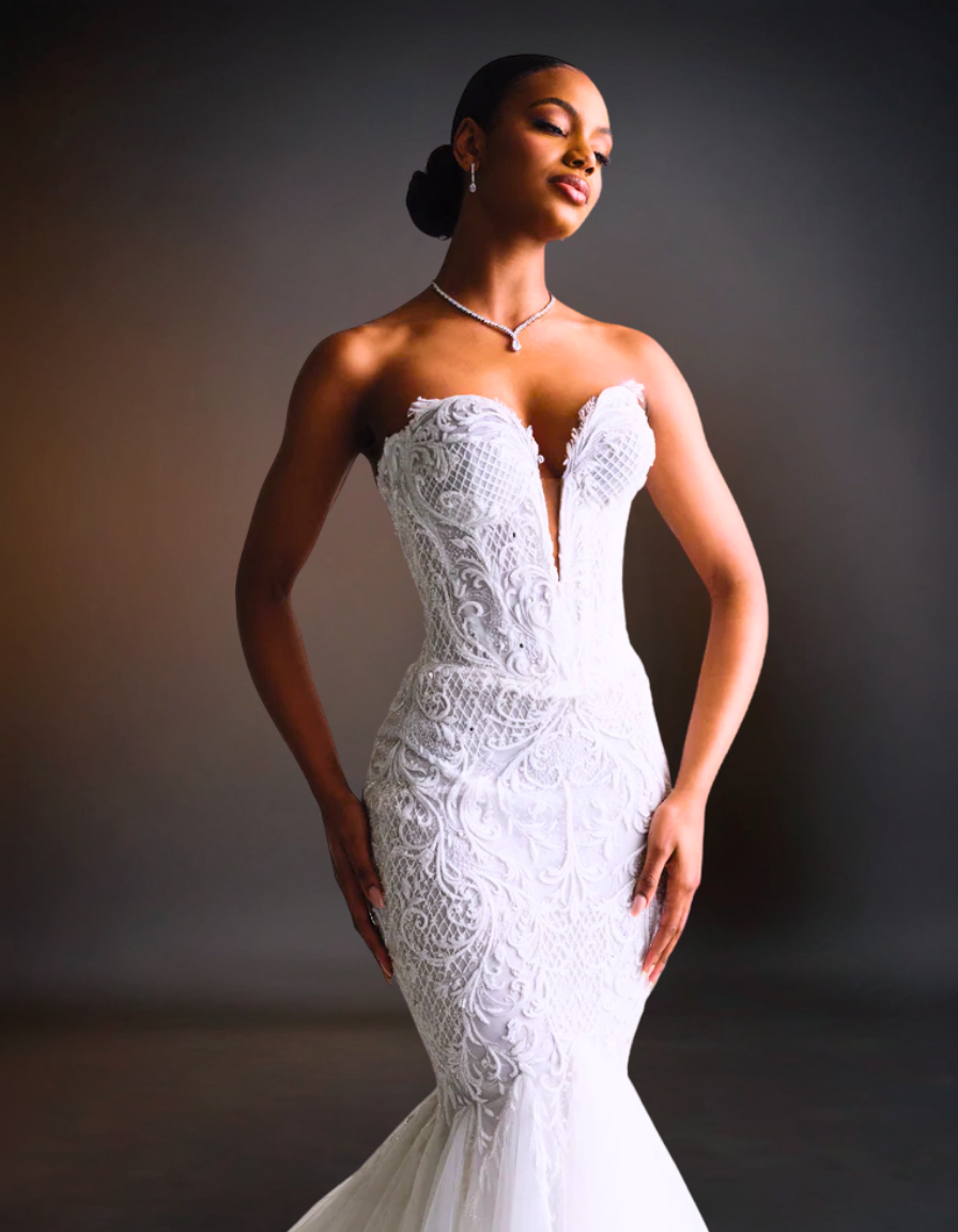 Woman wearing a white lace wedding dress against a dark background