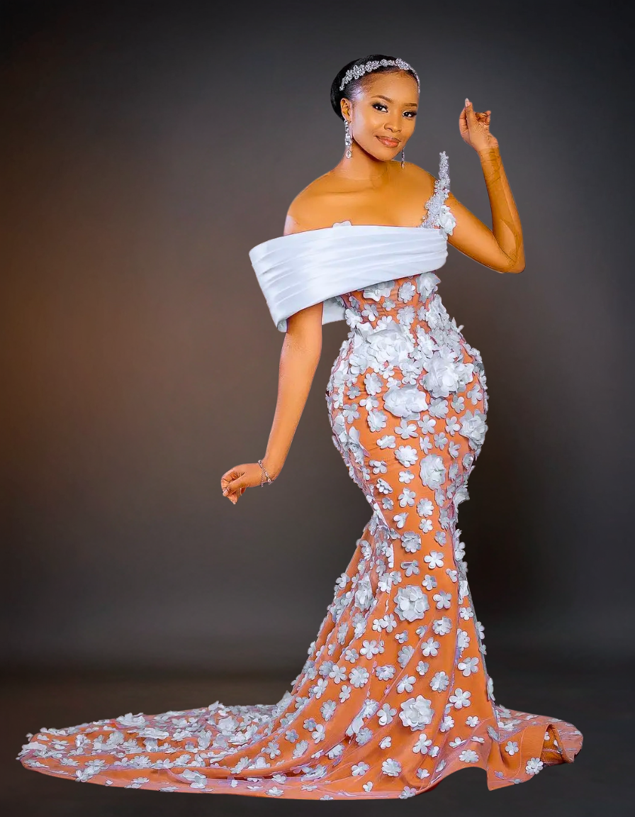 Woman in an elegant off-shoulder gown with floral details on a dark background