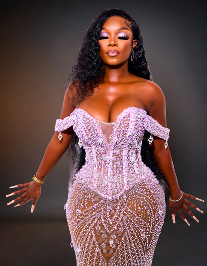 Woman wearing a sparkling pink off-shoulder dress against a dark background