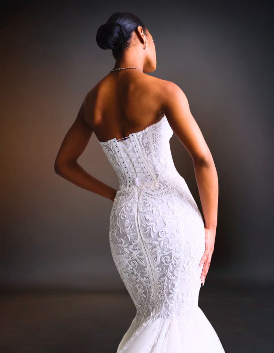 Woman wearing a white lace wedding dress against a dark background
