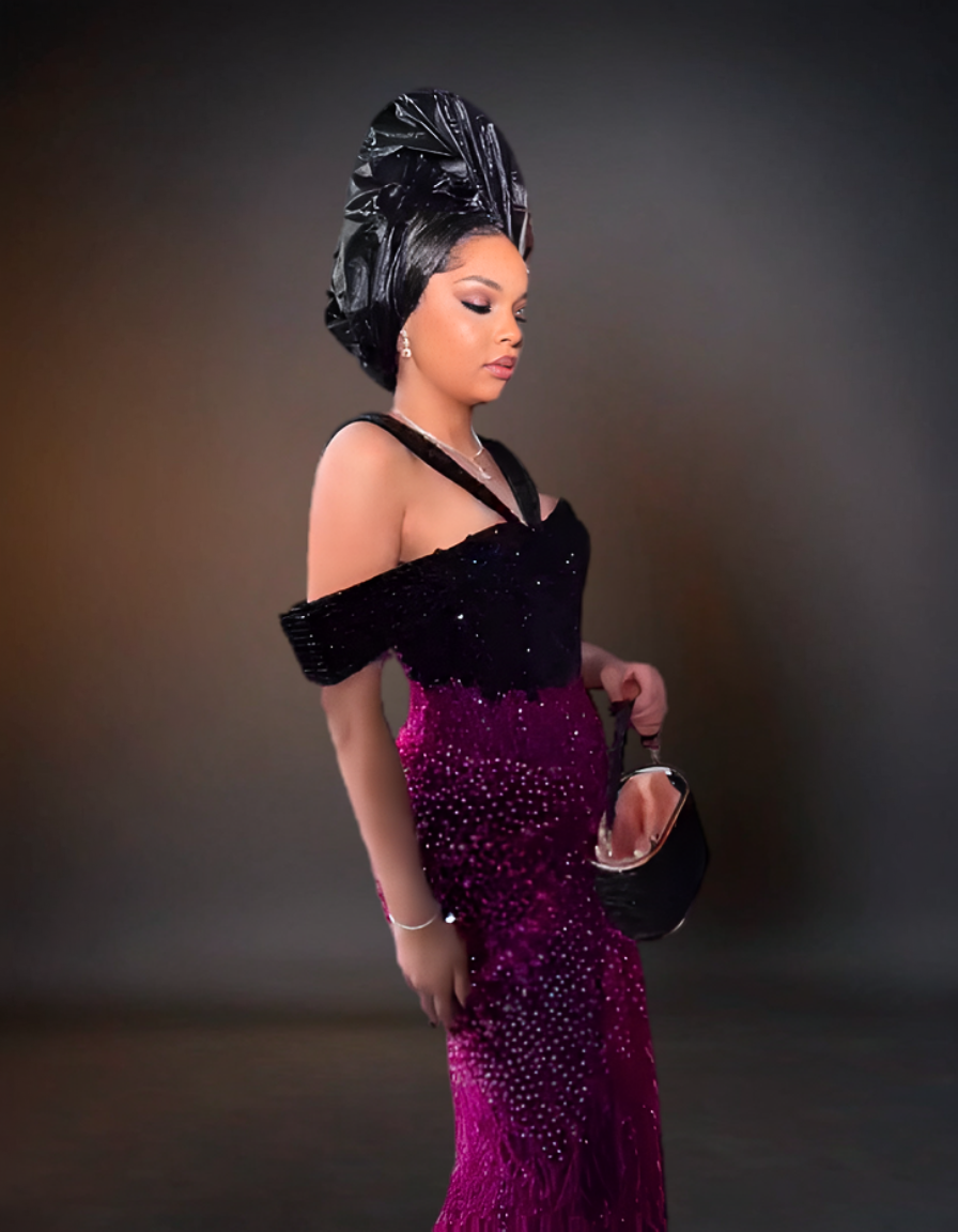 Woman in a black and purple dress with a headwrap against a dark background