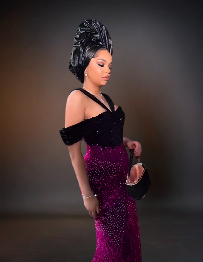 Woman in a black and purple dress with a headwrap against a dark background