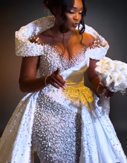 Woman in a sparkling white dress holding a bouquet against a dark background