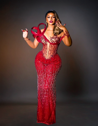 Woman wearing a red, intricately designed dress against a dark background