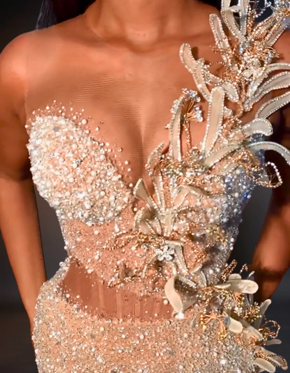 Close-up of a person wearing an ornate, beaded dress with floral details.